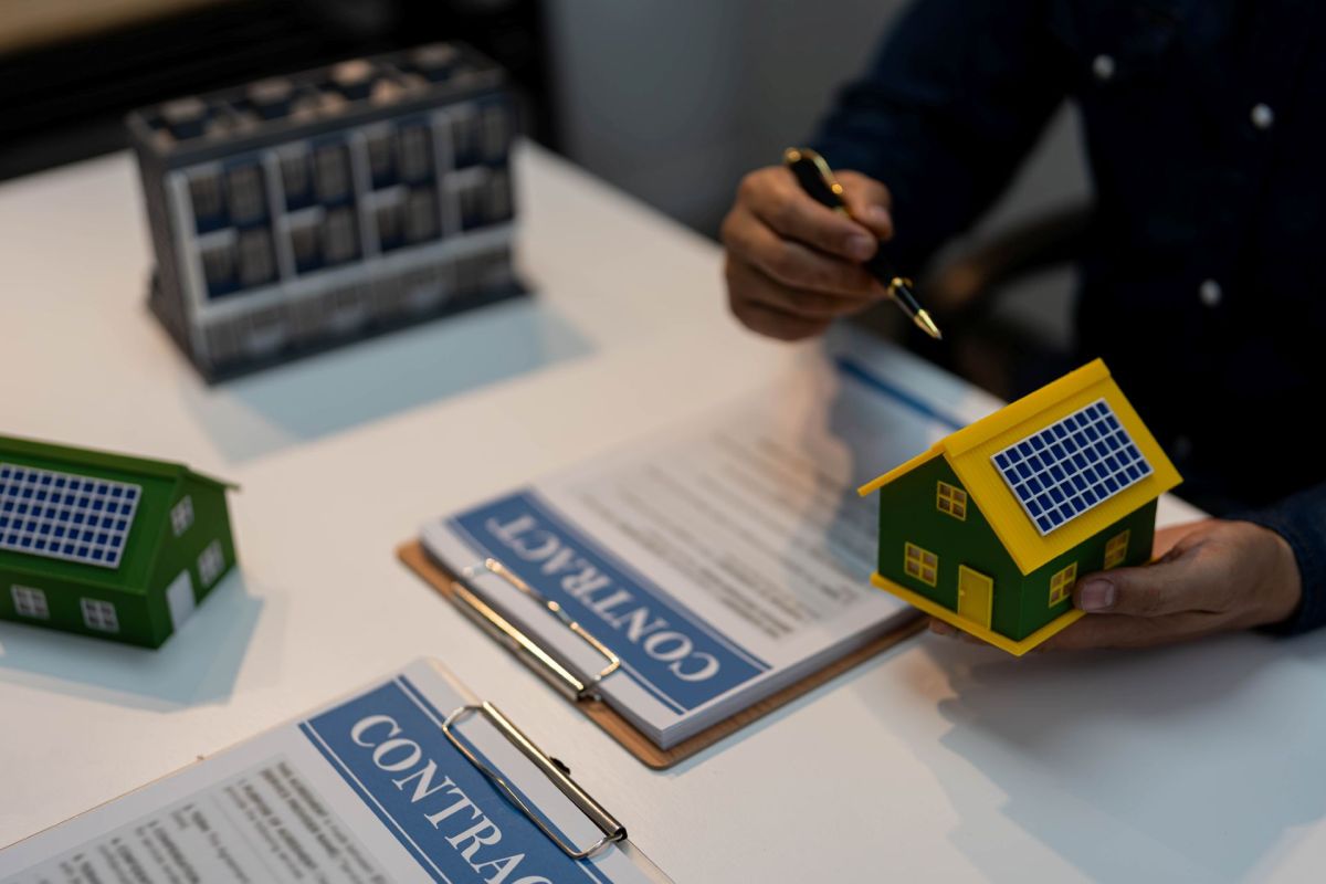 A person showing models for solar panels above a solar contract.
