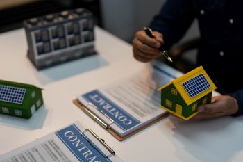 A person showing models for solar panels above a solar contract.