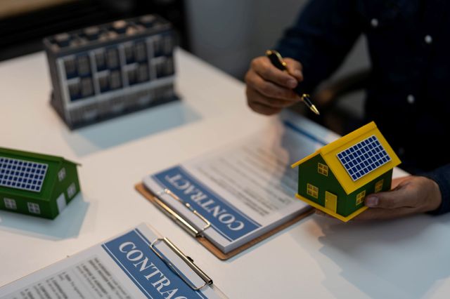 A person showing models for solar panels above a solar contract.