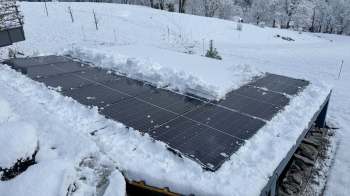 A snow-covered rooftop with solar panels partially buried under snow.