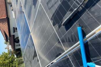 Solar panels on a rooftop with a cleaning tool in the foreground.