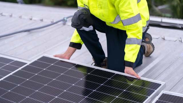 A worker in safety gear installing solar panels.