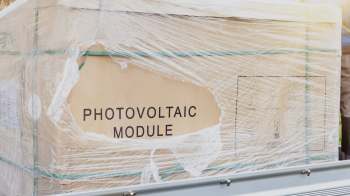 A cardboard box labeled "PHOTOVOLTAIC MODULE" wrapped in plastic.