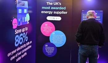 A person interacts with an Octopus Energy promotional display about energy savings and solar tariffs.