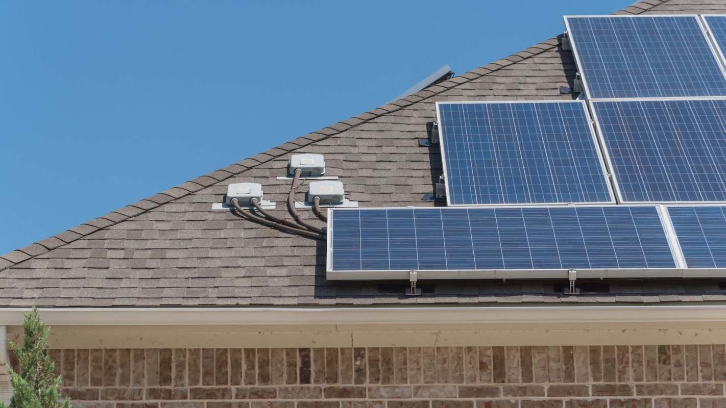 Solar panels installed on a roof with electrical components and clear blue sky in the background.