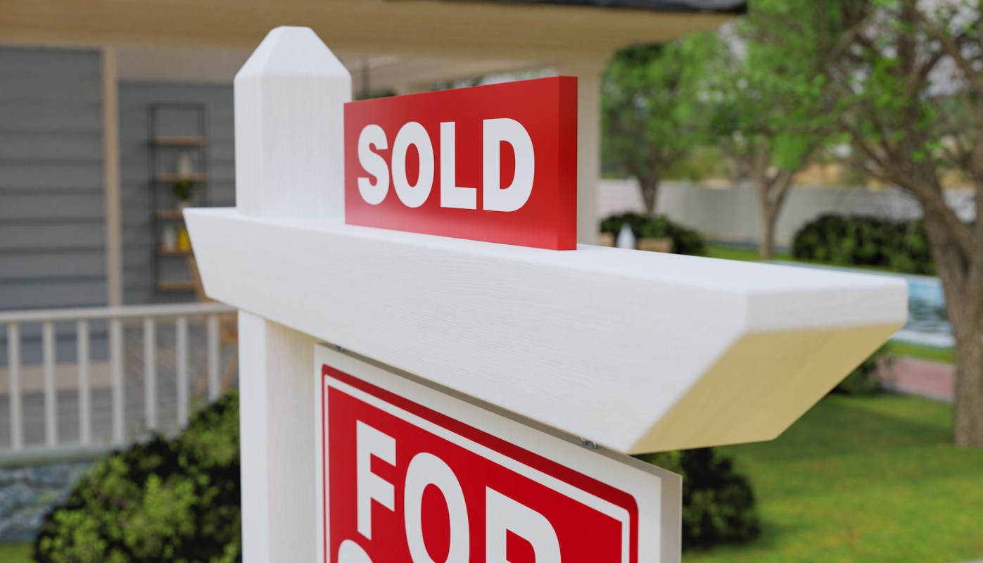 A real estate sign displaying "SOLD" in a residential area.