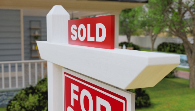 A real estate sign displaying "SOLD" in a residential area.