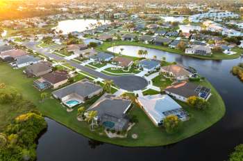 An aerial view of a suburban neighborhood with houses, streets, and a nearby pond.