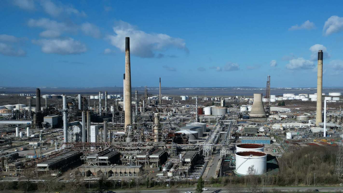 An industrial area with various structures, including tall chimneys and storage tanks.