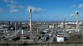 An industrial area with various structures, including tall chimneys and storage tanks.