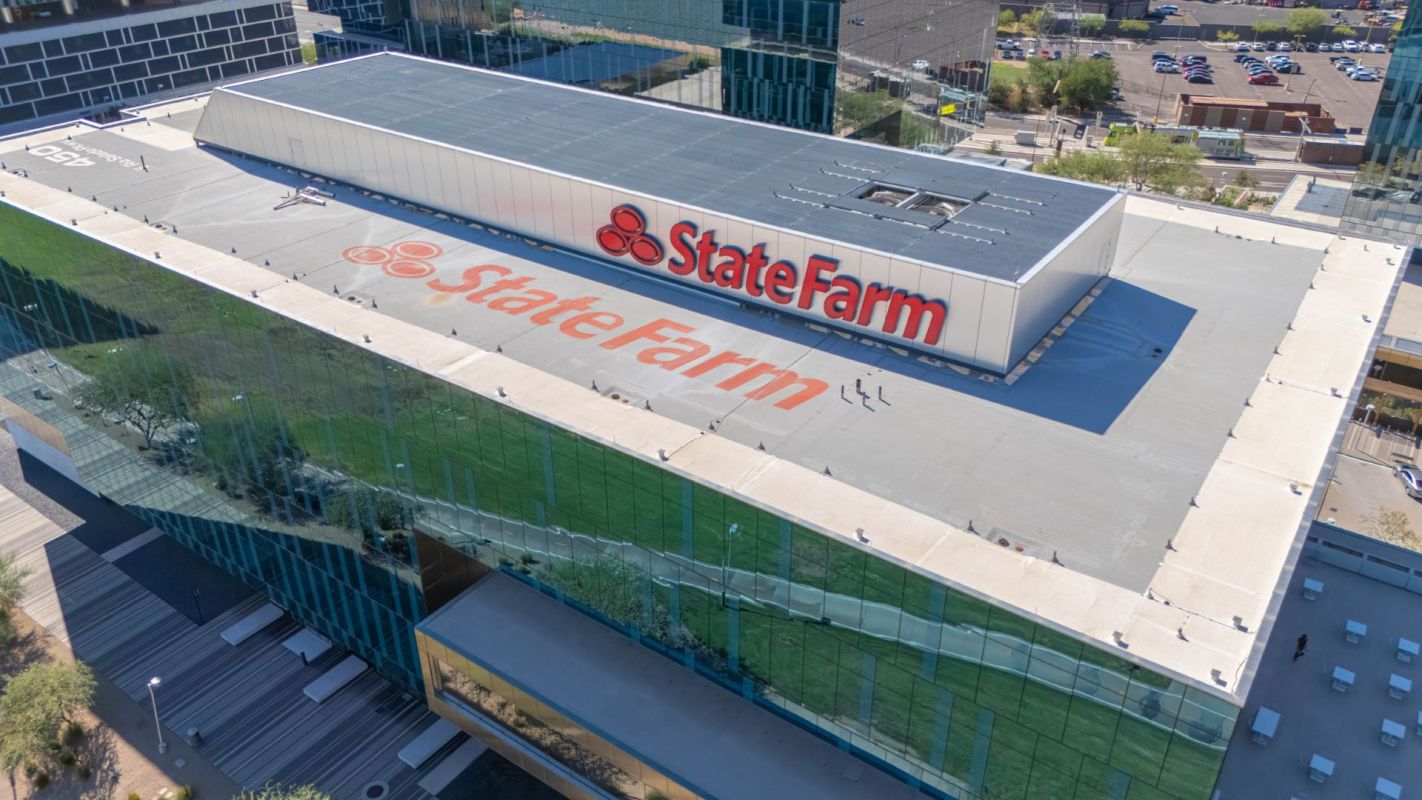 The roof of a building displaying the State Farm logo, surrounded by reflective glass windows.
