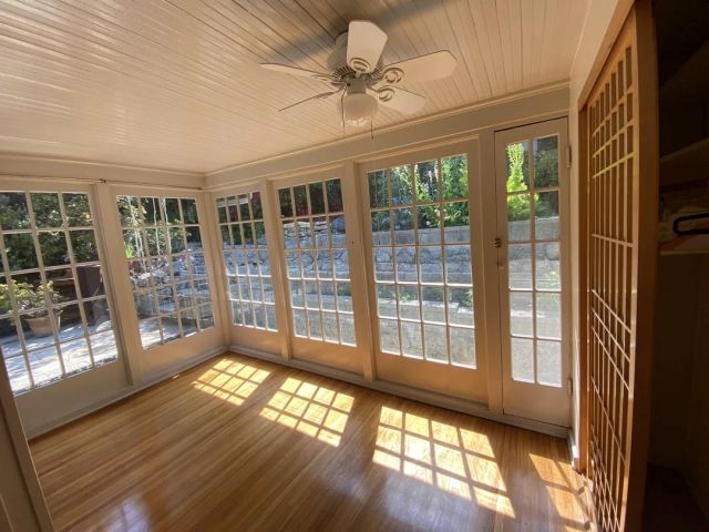 A sunroom with wood floors and single-pane windows. 