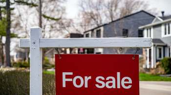 A "For Sale" sign in front of residential houses.
