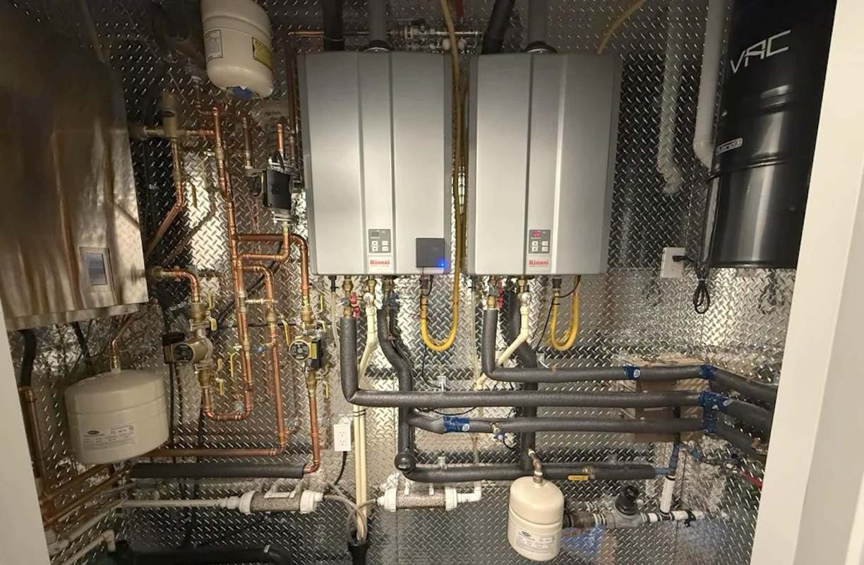 A system of water pipes and heaters installed on a metallic wall.