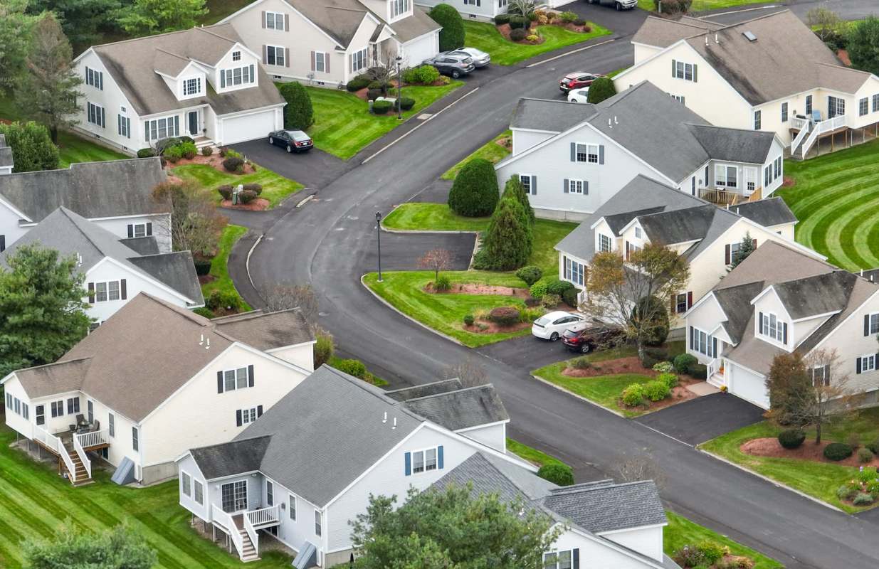 Aerial view of a neighborhood with houses, roads, and landscaped lawns.