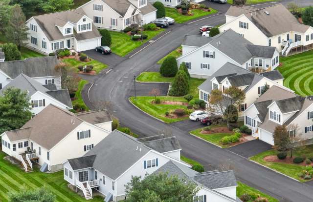 Aerial view of a neighborhood with houses, roads, and landscaped lawns.