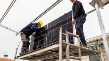 Two workers installing solar panels.