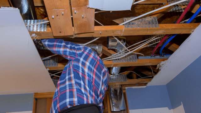 A person looking at ductwork.