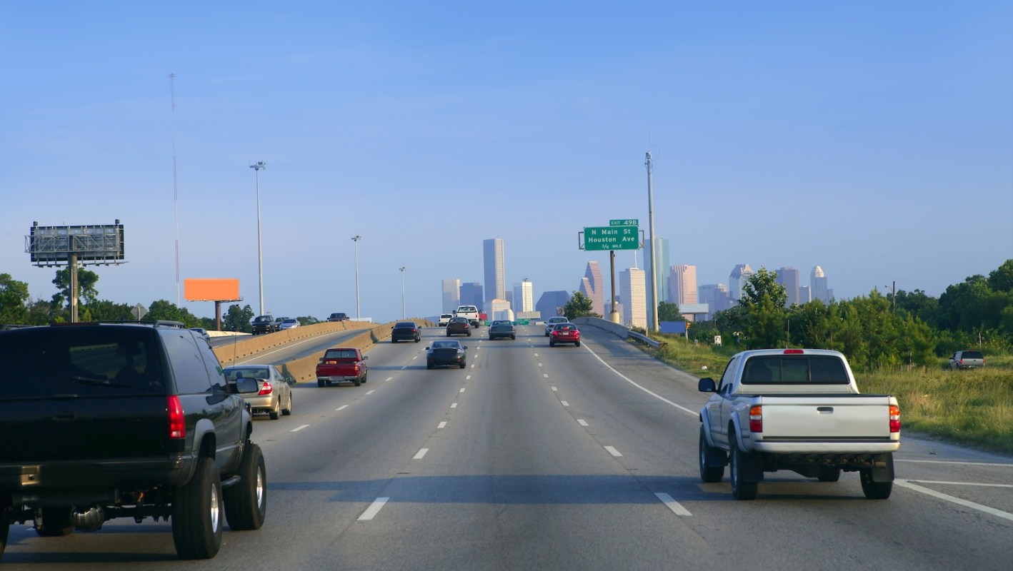 A busy highway with various vehicles and a city skyline in the background.