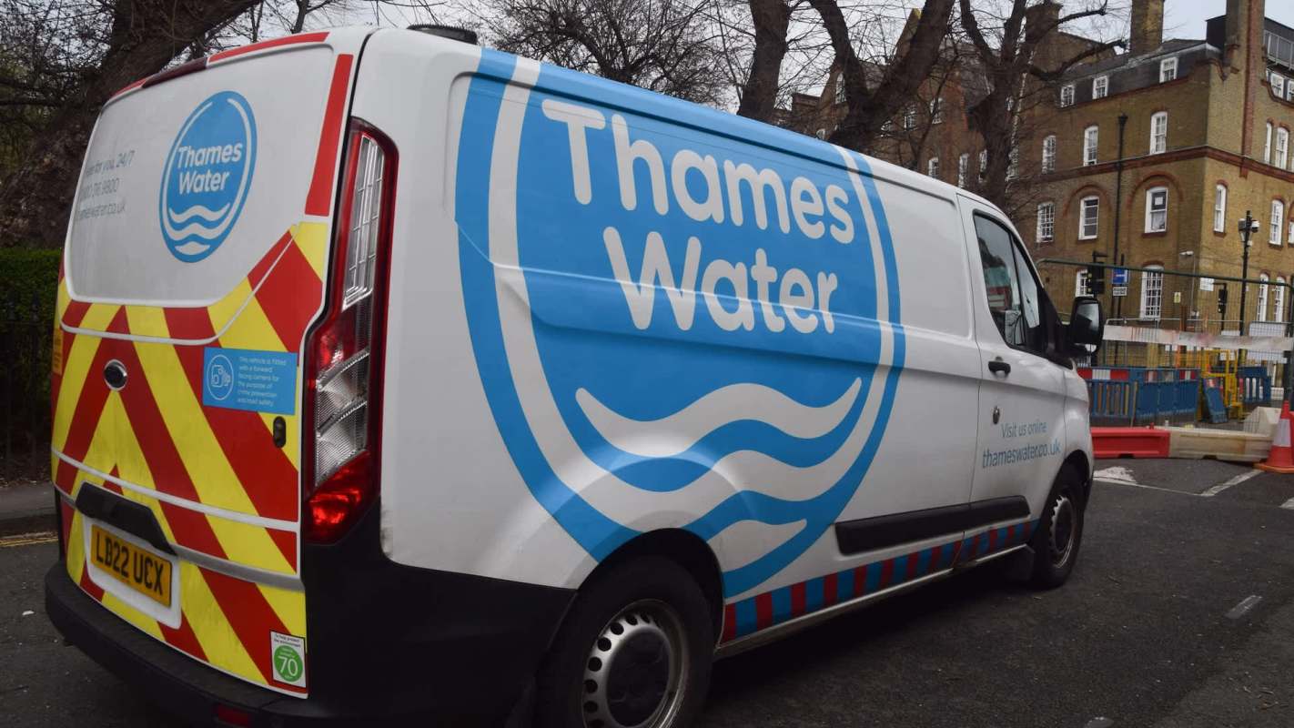A Thames Water van parked near construction barriers and trees.