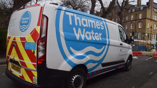A Thames Water van parked near construction barriers and trees.