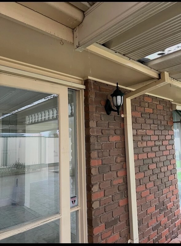 Water is cascading down a window, creating a misted effect on the glass near a brick wall.