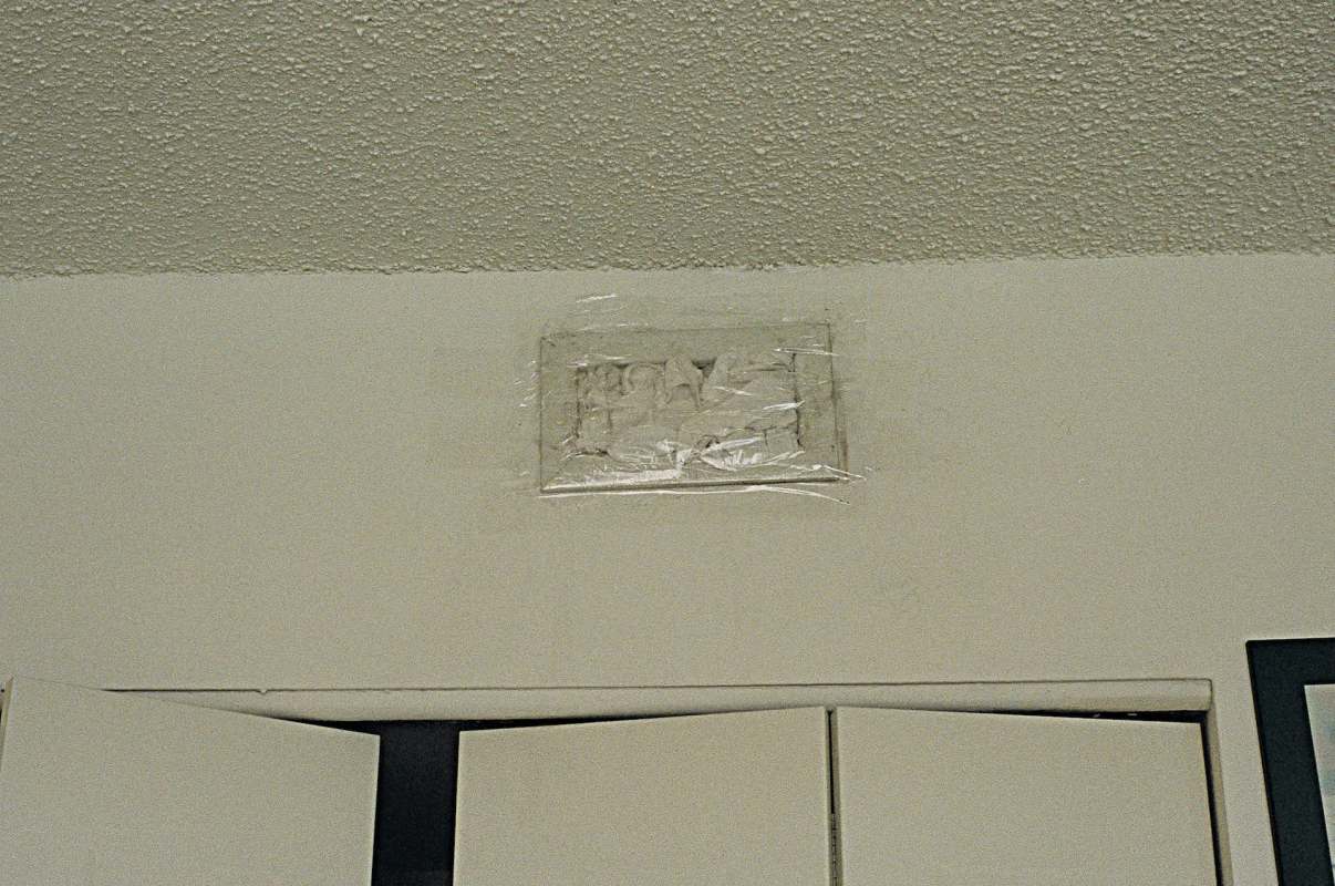 An object covered in plastic is attached to a wall near a set of doors.