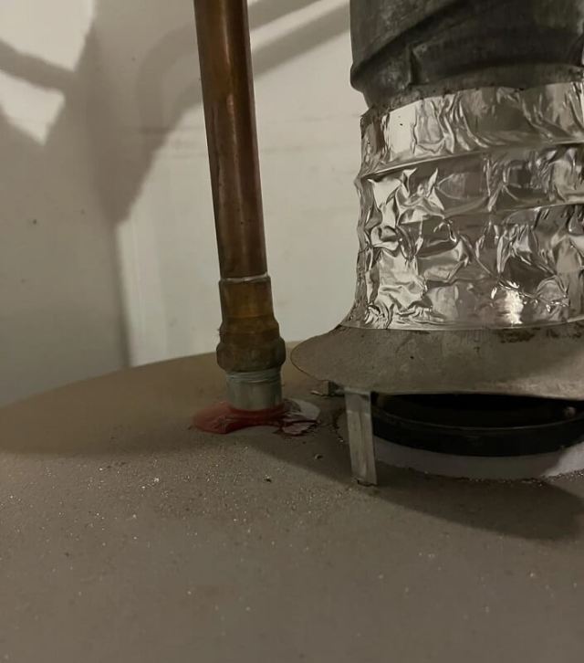 A metallic pipe connection on a water heater with a valve, showing a green stain from a blue plastic piece.