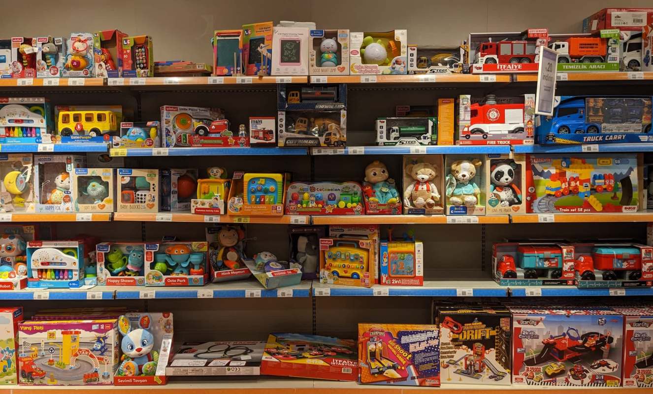 A store shelf filled with various children's toys, including vehicles, plush animals, and educational games.