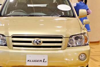 A gold SUV with a visible logo and a tag labeled "KLUGER L" in a showroom.