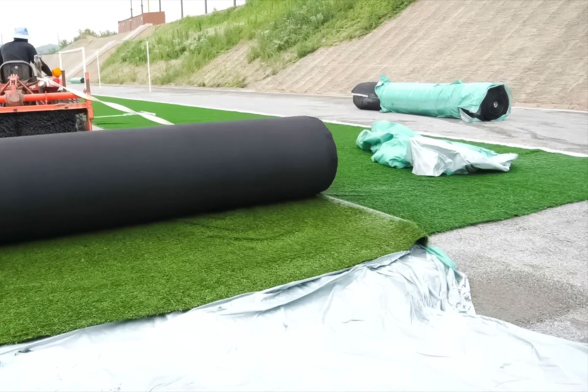 A worker installing artificial turf.