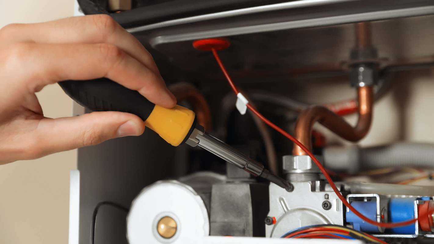A technician working on a boiler with a screwdriver.