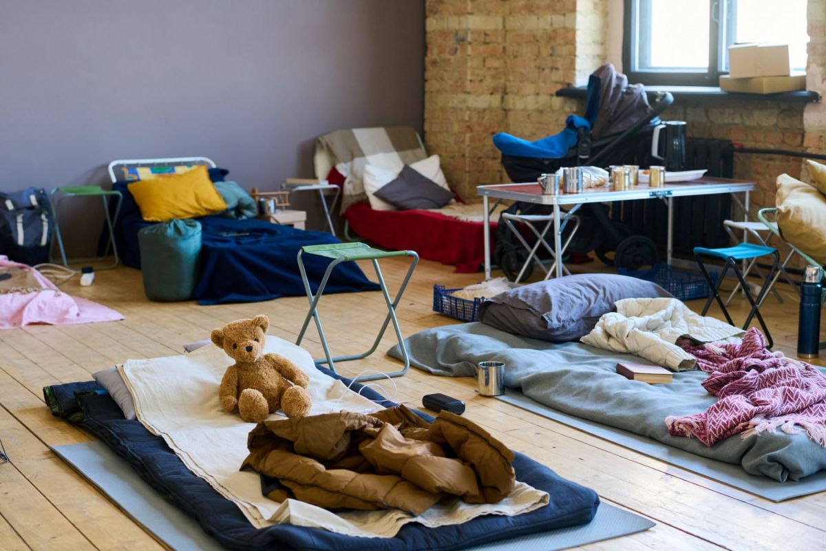 Sleeping bags and beds on a wooden floor.