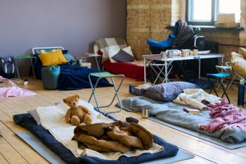 Sleeping bags and beds on a wooden floor.