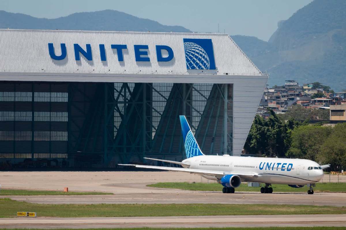 A United Airlines plane on the tarmac in front of a large hangar with the United logo.