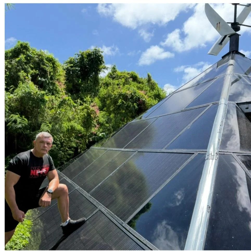 A man standing with his foot on a wall of solar panels.
