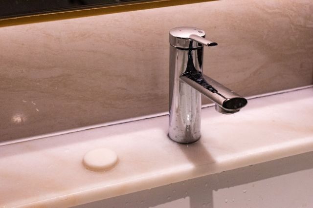 A chrome faucet on a marble countertop next to a round soap disc.