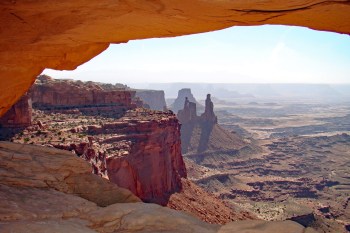 A panoramic view of a desert landscape with red rock formations and distant mesas.