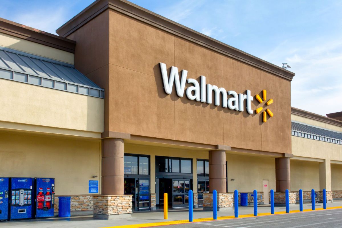 A Walmart store exterior with a vending machine and blue poles in front.