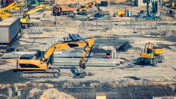 Construction site featuring various heavy machinery, including excavators and dump trucks, with piles of materials.