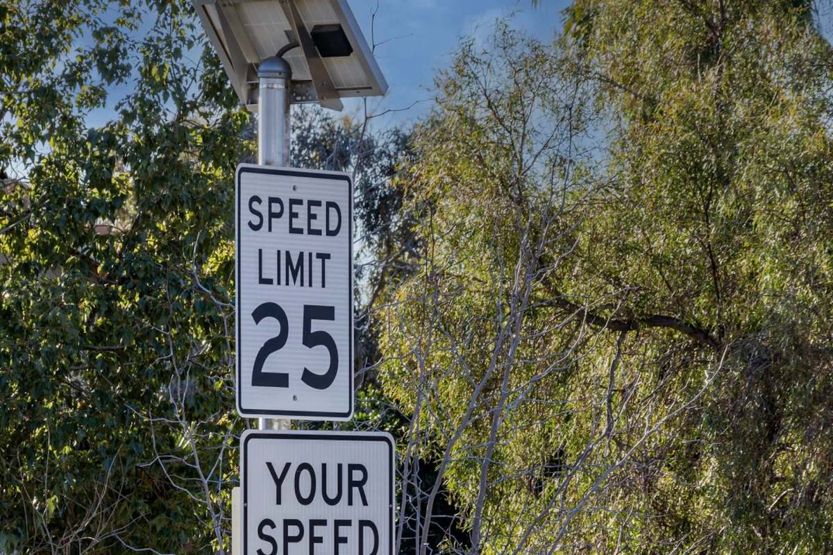 A speed limit sign indicating 25 mph, next to a sign displaying the driver's current speed.