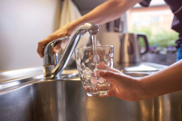 A person filling a glass with water.