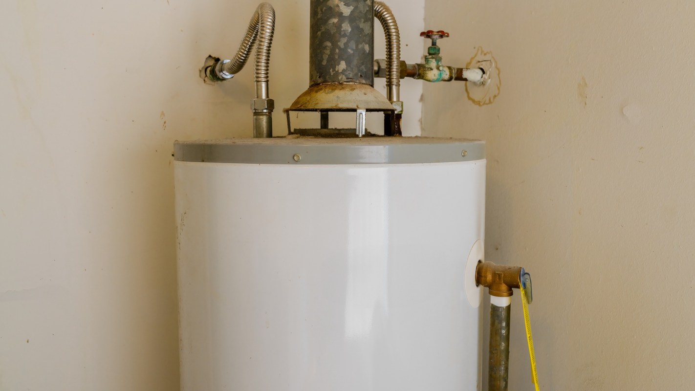A white water heater with connected pipes against a wall.