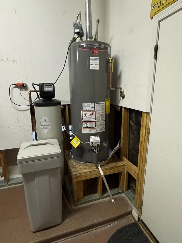 A person uses a wrench to tighten valves on a water heater.