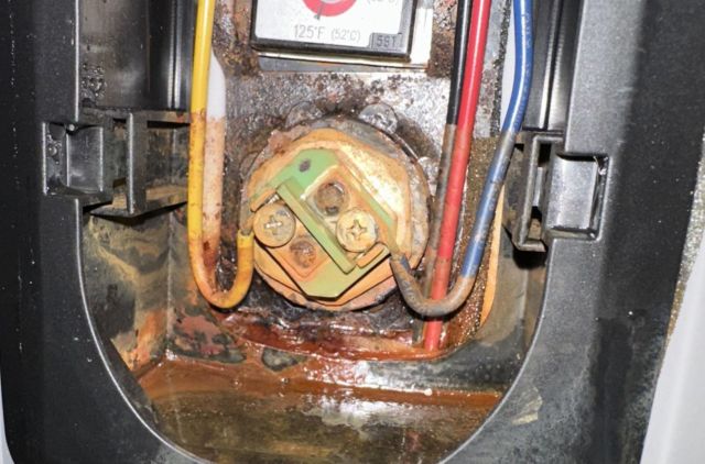 A rusted electrical component with visible corrosion and leaking liquid.