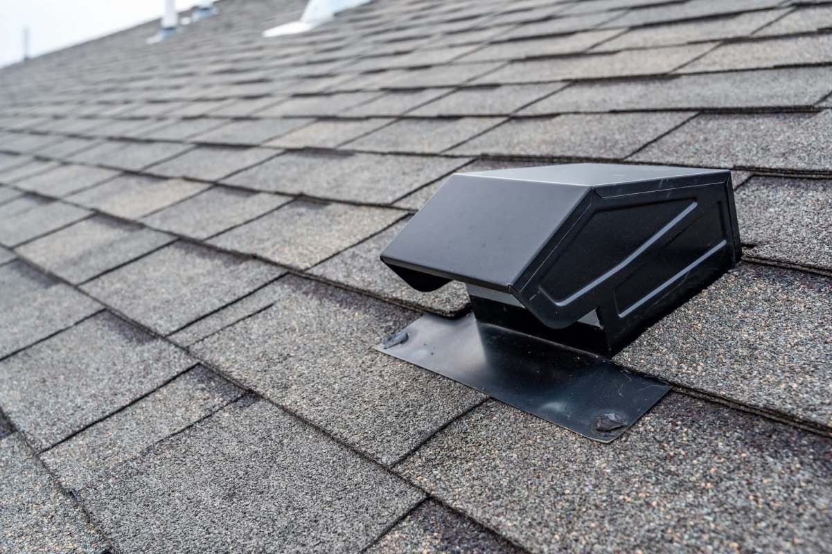A black vent pipe on a textured asphalt shingle roof.