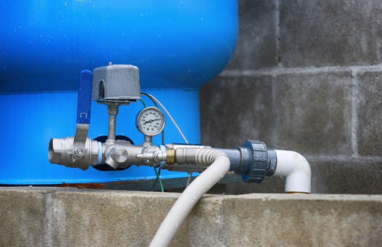A water well pressure gauge and tank.