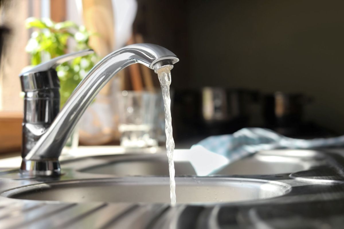 Water running out of a faucet and into a kitchen sink.