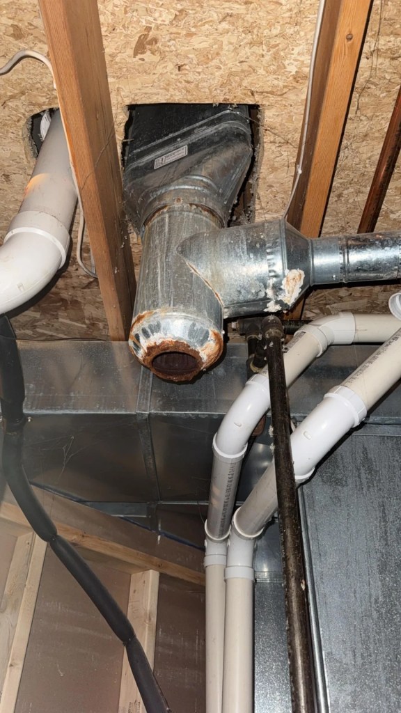 A metal vent pipe with a rusted hole.