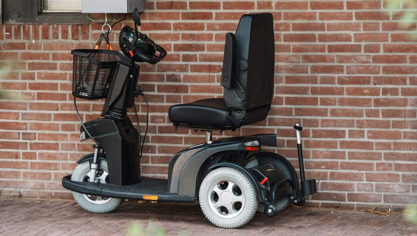 An electric mobility scooter positioned against a brick wall.